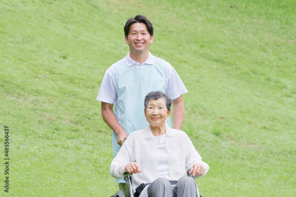 介護士と車椅子に乗る高齢者　屋外