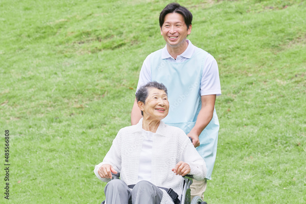 介護士と車椅子に乗る高齢者　屋外