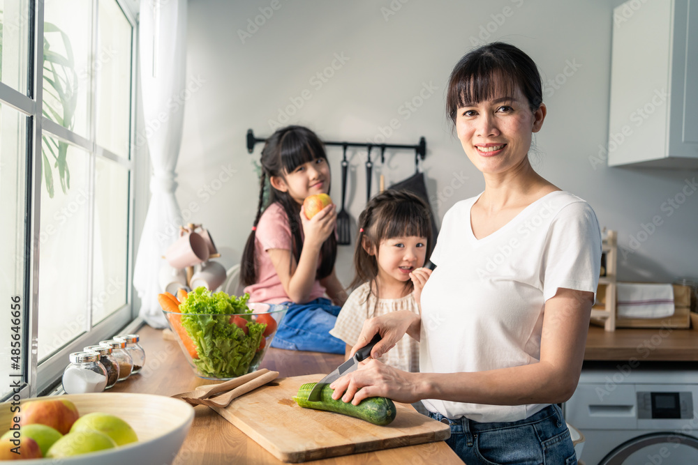 亚洲可爱的母亲在厨房里和年幼的女儿一起做早餐。