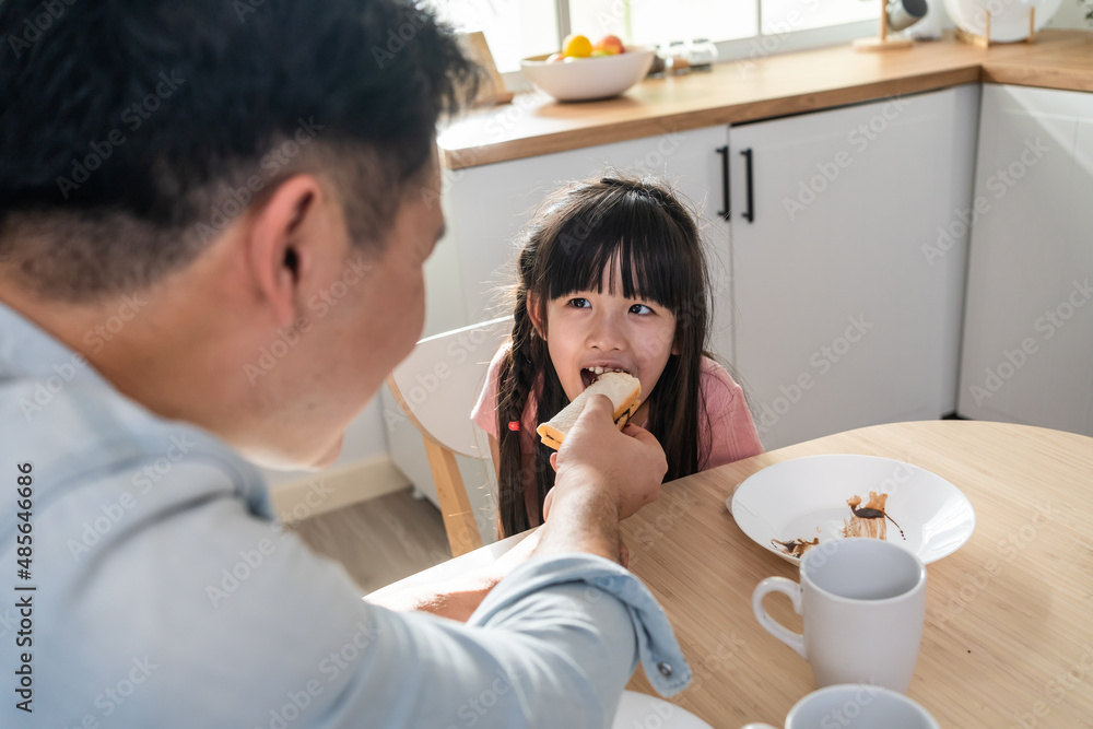 Asian attractive father taking care of young kid daughter in kitchen. 