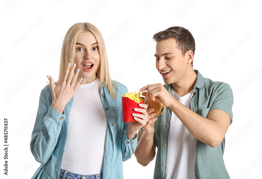 Happy young couple with french fries and burger on white background