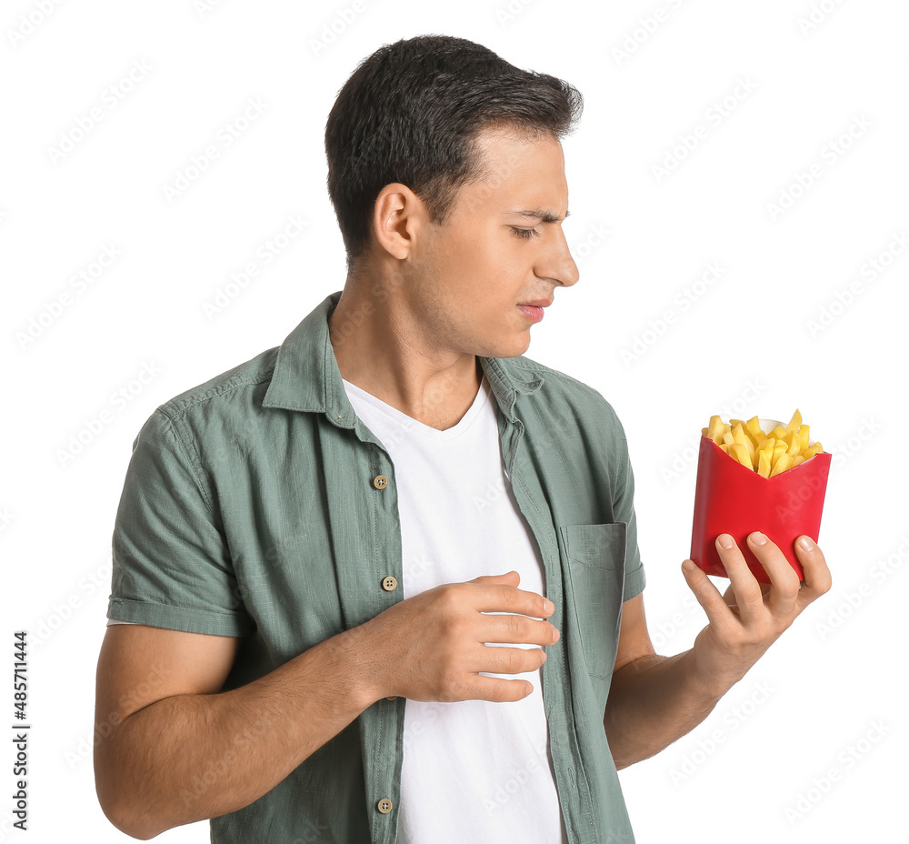 Stressed young man with french fries on white background