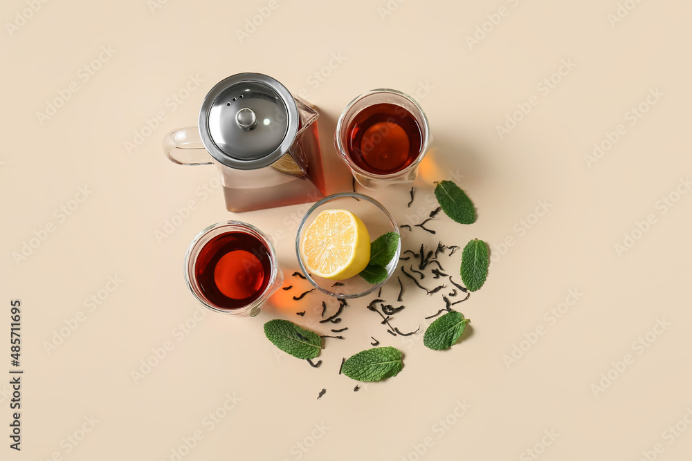 Composition of teapot and glass with tasty tea on yellow background