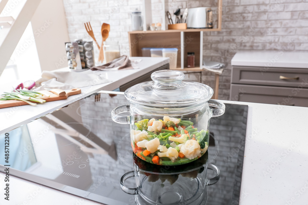 Cooking pot with healthy vegetables on electric stove in kitchen