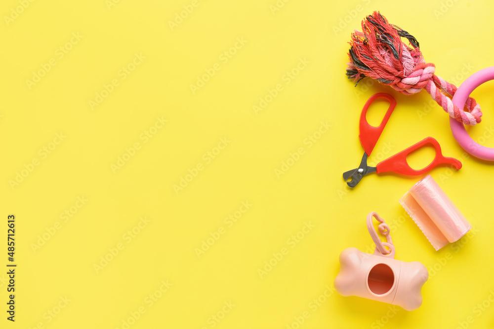 Dispenser, pet waste bags, toy and nail clipper on yellow background