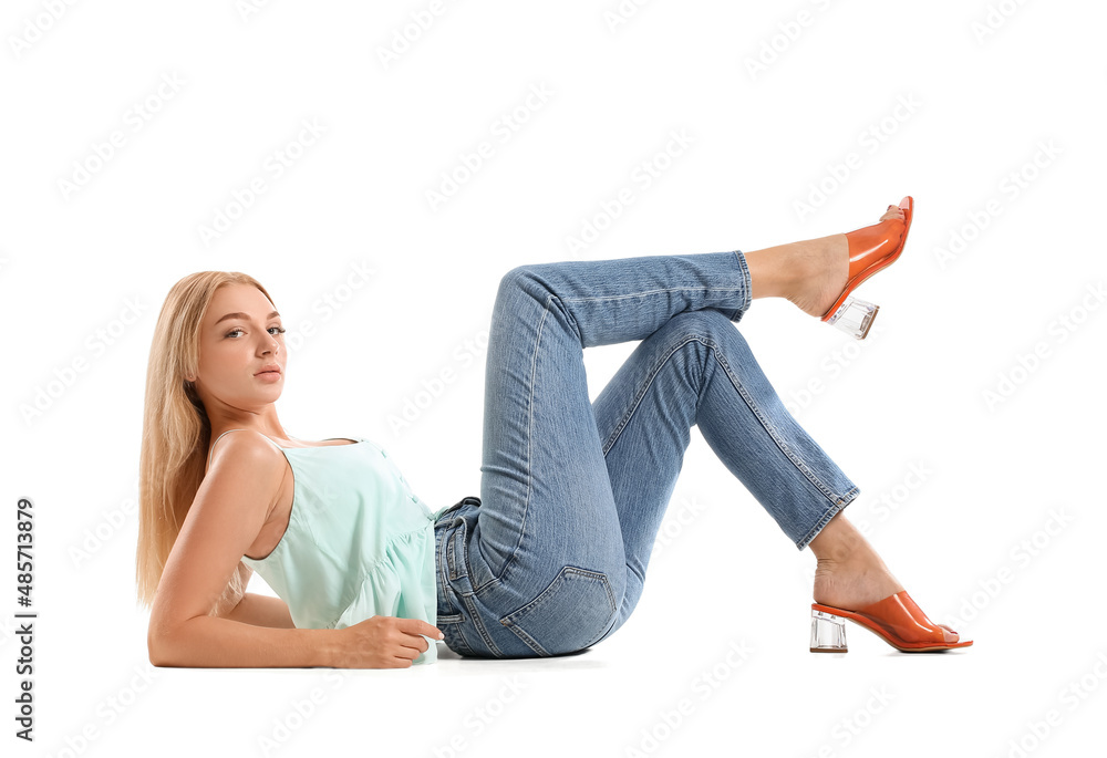 Fashionable young woman in stylish jeans on white background