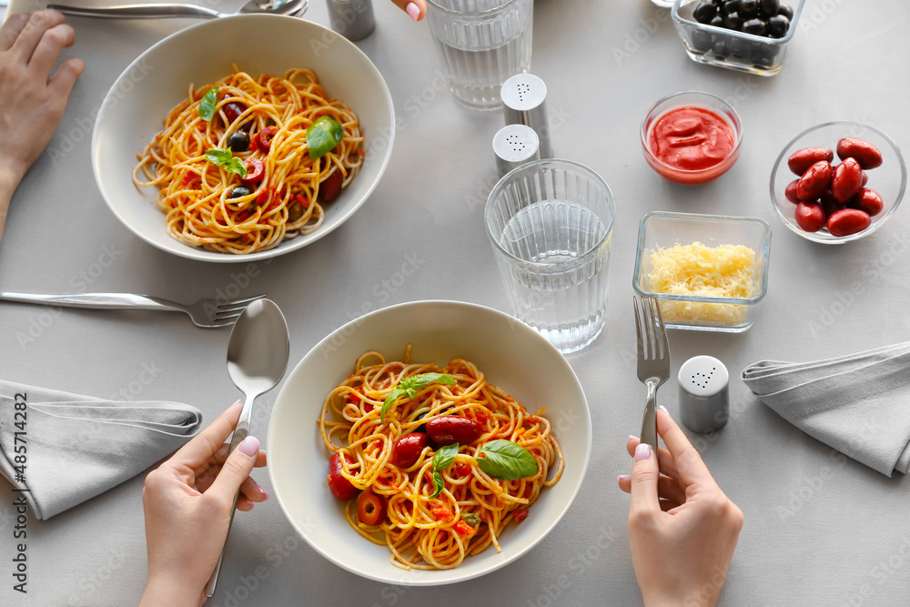 Woman eating Pasta Puttanesca at table in restaurant