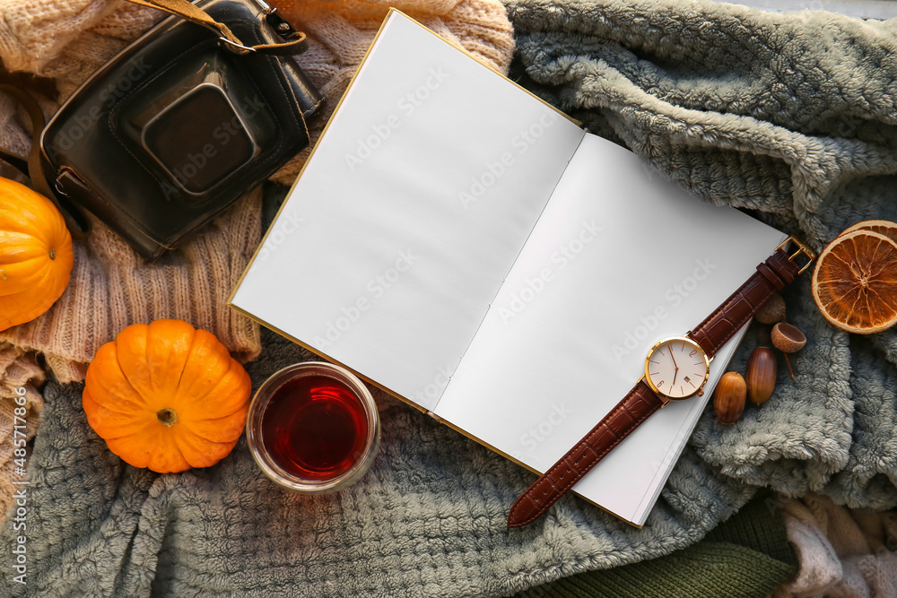 Blank book, cup of tea and wristwatch on plaid