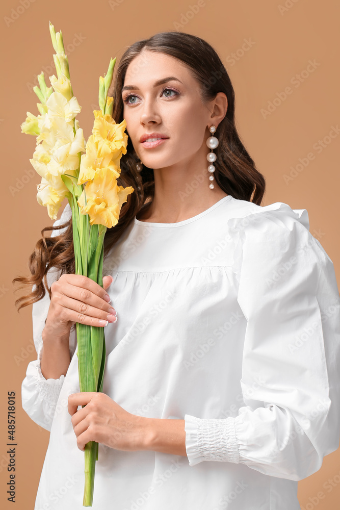 Woman with beautiful earrings holding bouquet of Gladiolus flowers on color background