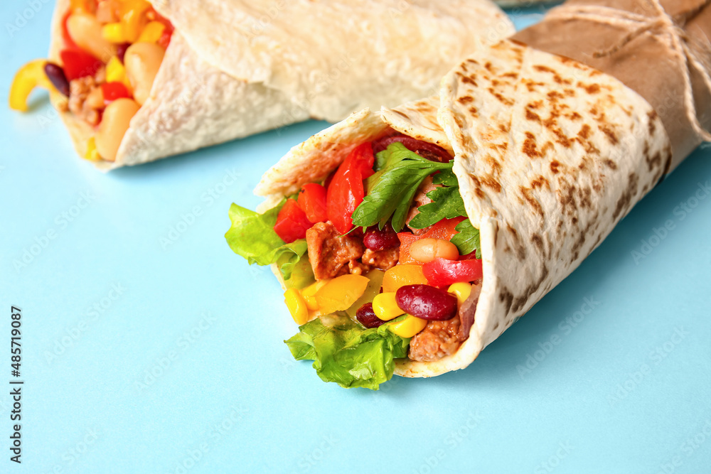 Delicious burritos on blue background, closeup