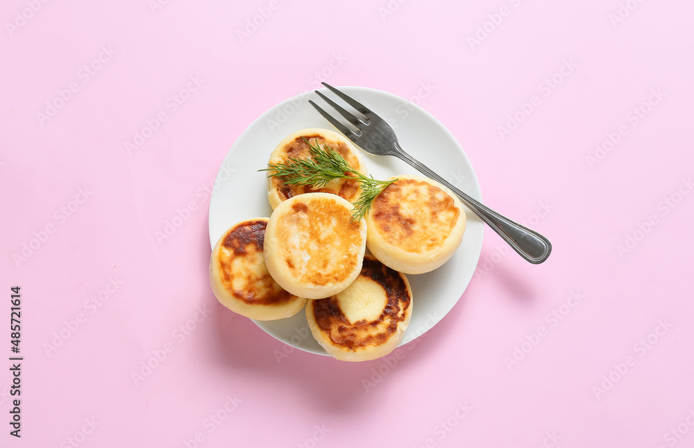 Plate with tasty cottage cheese pancakes on pink background