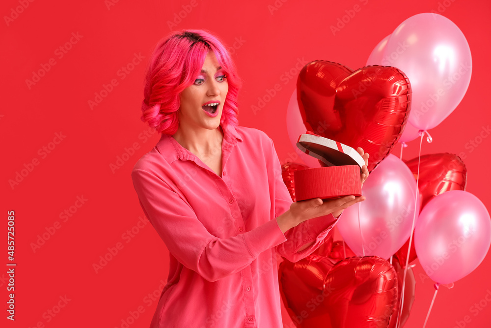 Surprised woman with bright hair opening gift on color background. Valentines Day celebration