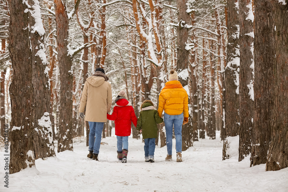 Happy family walking in forest on snowy winter day