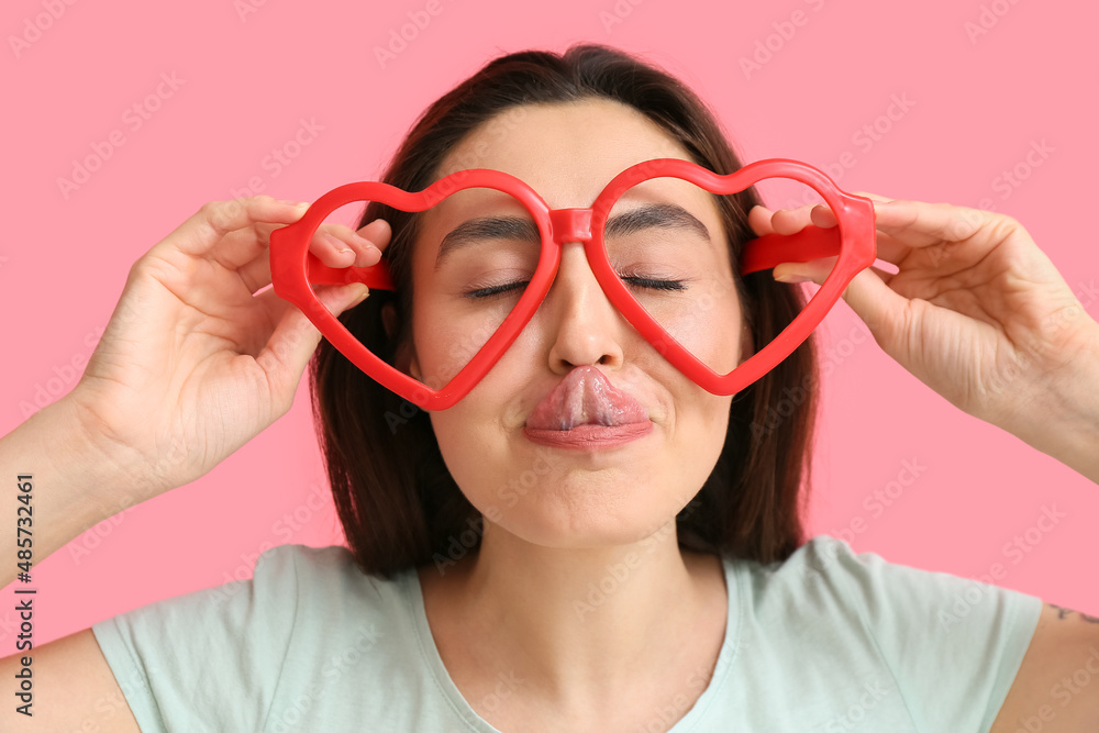 Young woman in funny disguise on pink background. April fools day celebration