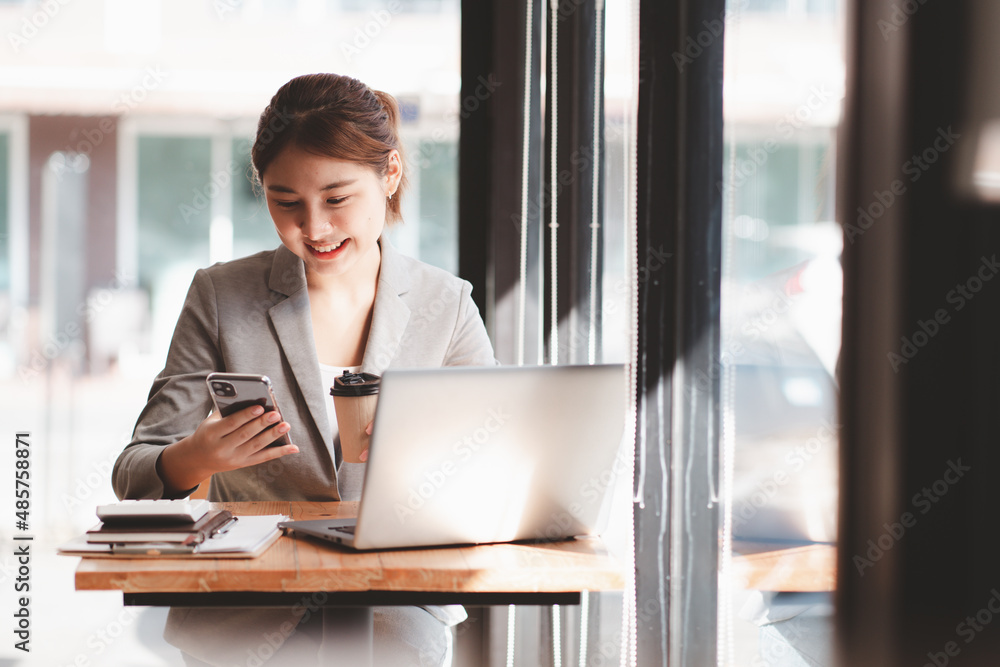 Protrait of Beautiful businesswoman sitting at desk and working with laptop computer and smartphone.