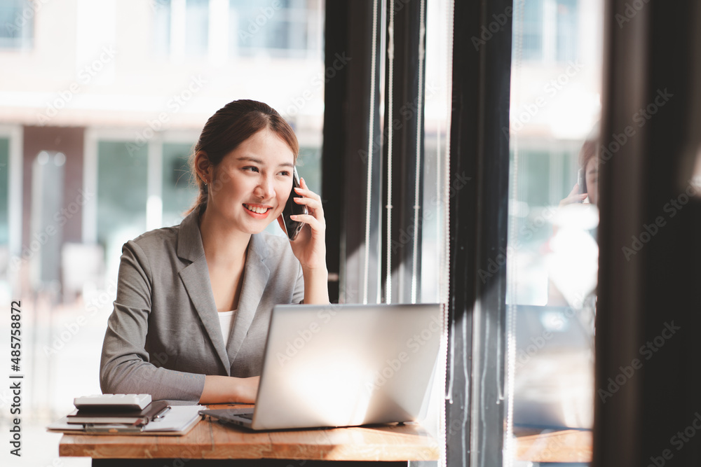 Protrait of Beautiful businesswoman sitting at desk and working with laptop computer and smartphone.