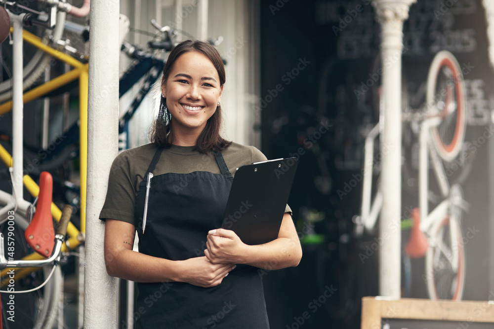 我今天能帮你什么？一个漂亮的年轻女人独自站在自行车店外的照片