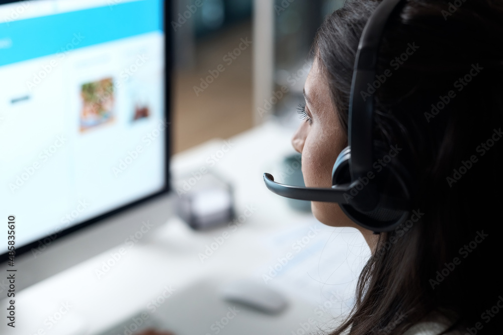 Fully skilled in providing quality customer support. Shot of a young woman using a headset and compu