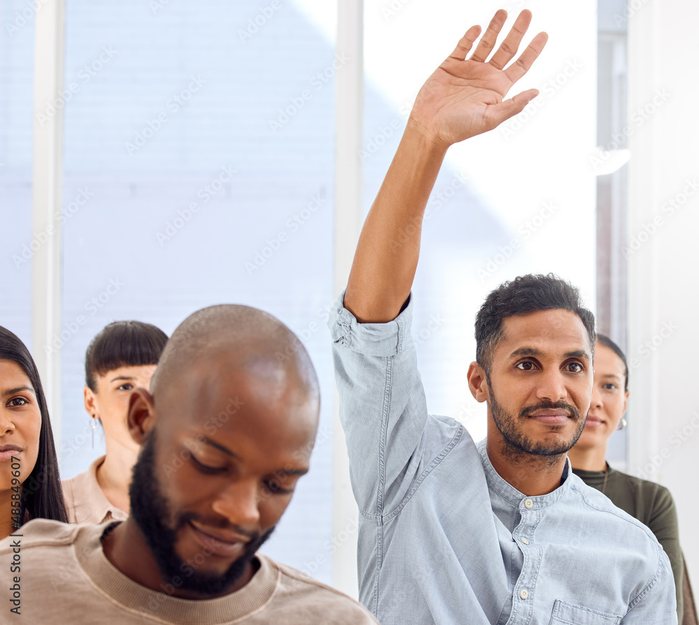 I have a question. Shot of a young businessman raising his hand during a presentation in an office.