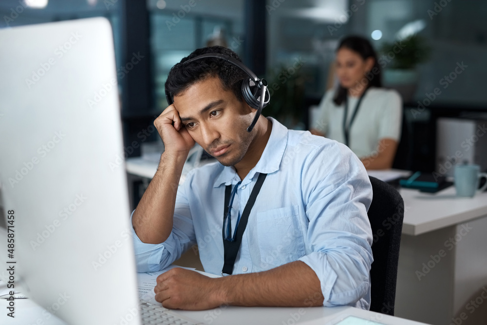 Rude callers really do my head in. Shot of a young man using a headset and looking depressed in a mo