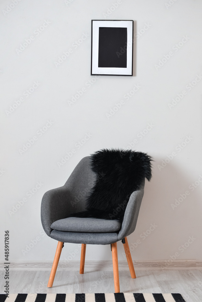 Stylish grey armchair near light wall in room