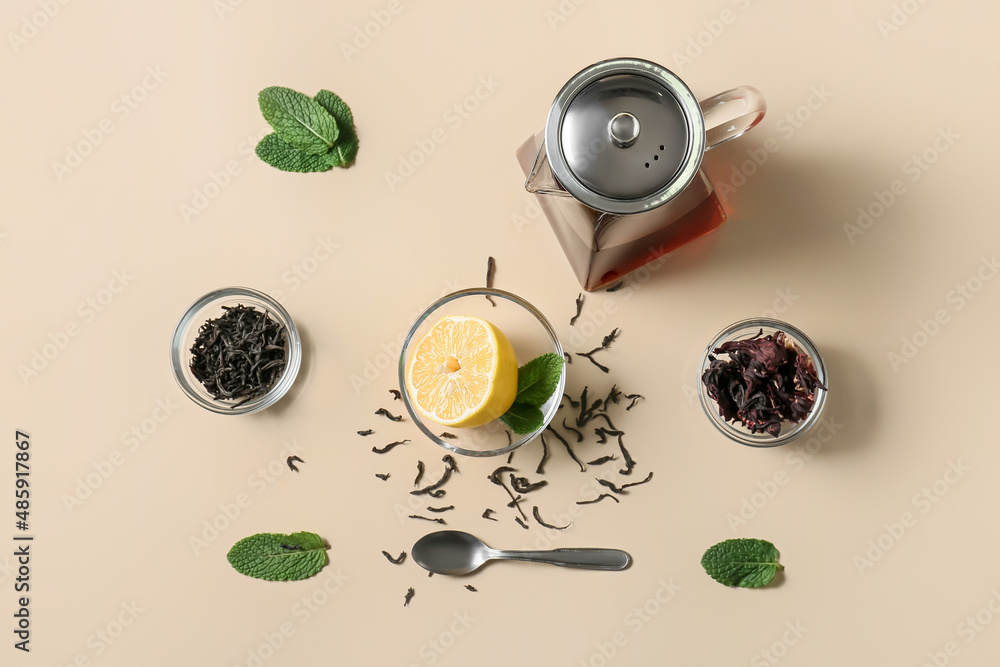 Composition of teapot with tasty tea and glass with lemon on yellow background