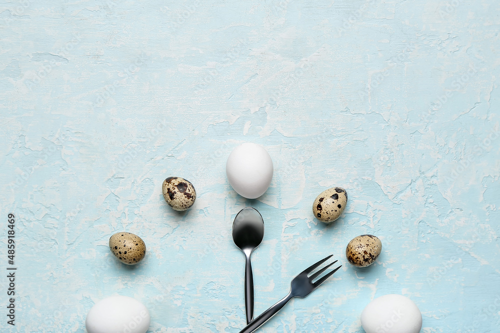 Clock made of eggs and cutlery on color background, closeup