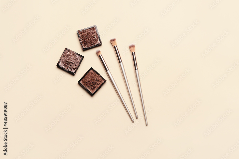 Makeup brushes and eye shadow palettes on light background