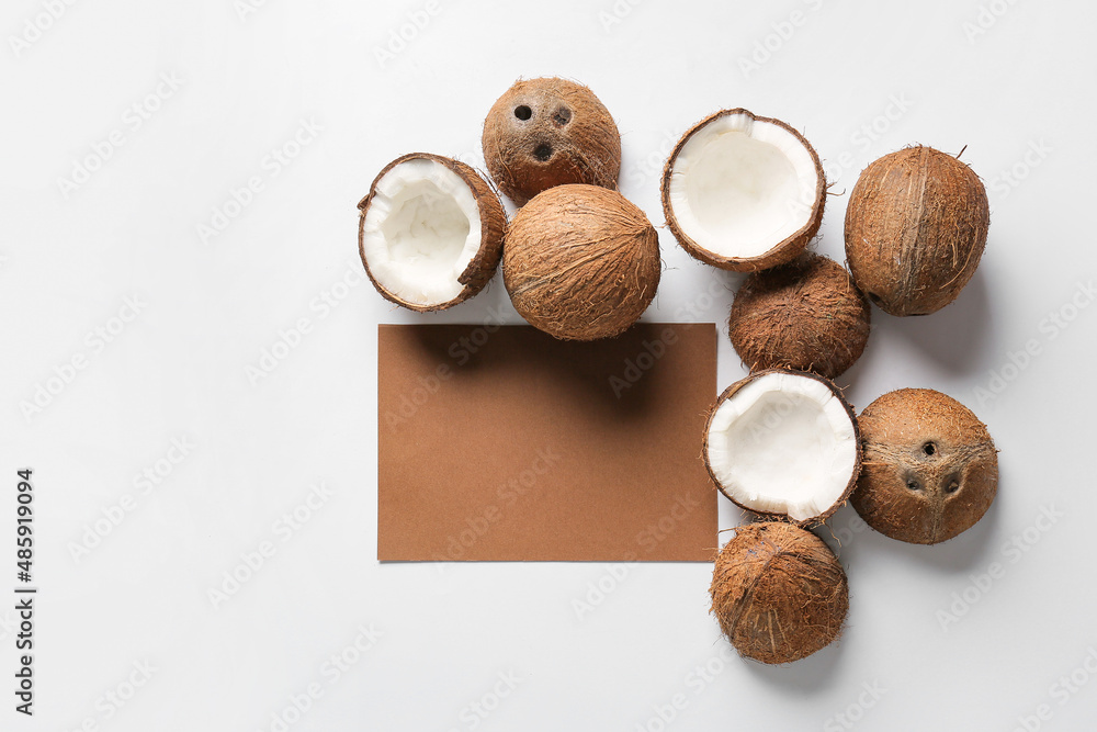 Composition with blank card and ripe coconuts on white background