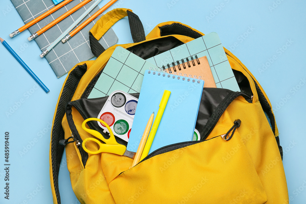 Stylish school backpack with stationery on color background, closeup