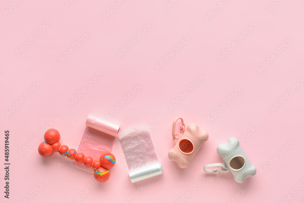 Dispensers with pet waste bags and toy on pink background