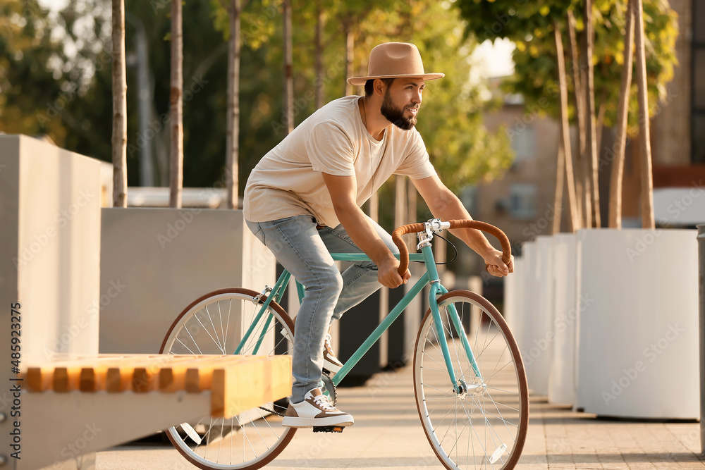 Handsome bearded man riding bicycle in city