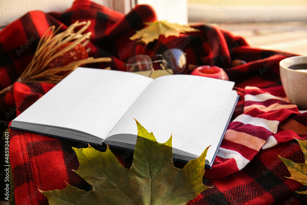 Blank book and autumn decor on plaid in room, closeup