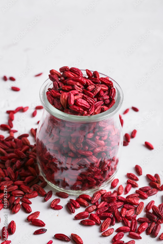 Jar with dried barberries on light background