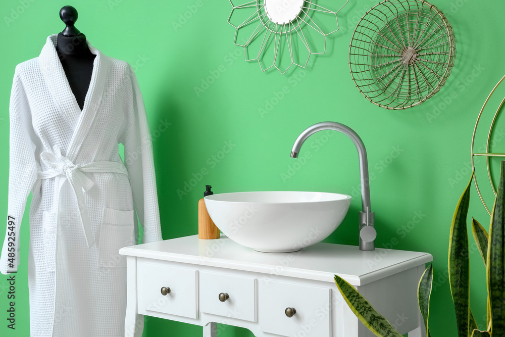 White table with sink and soap near green wall in bathroom