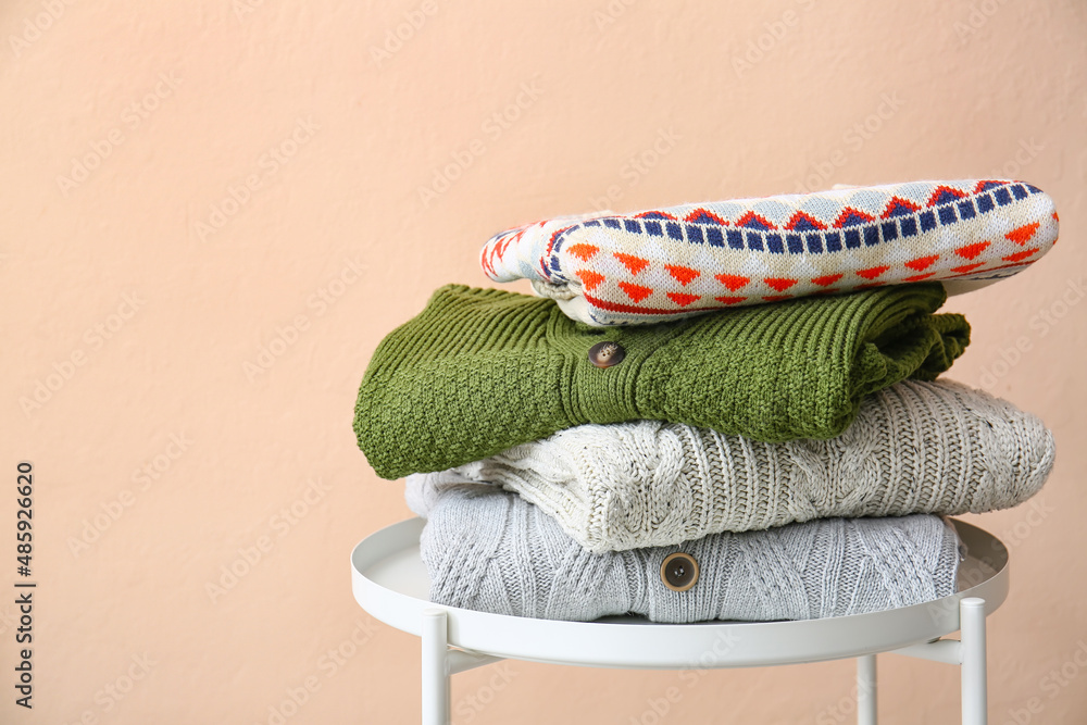 Stack of sweaters on table near color wall