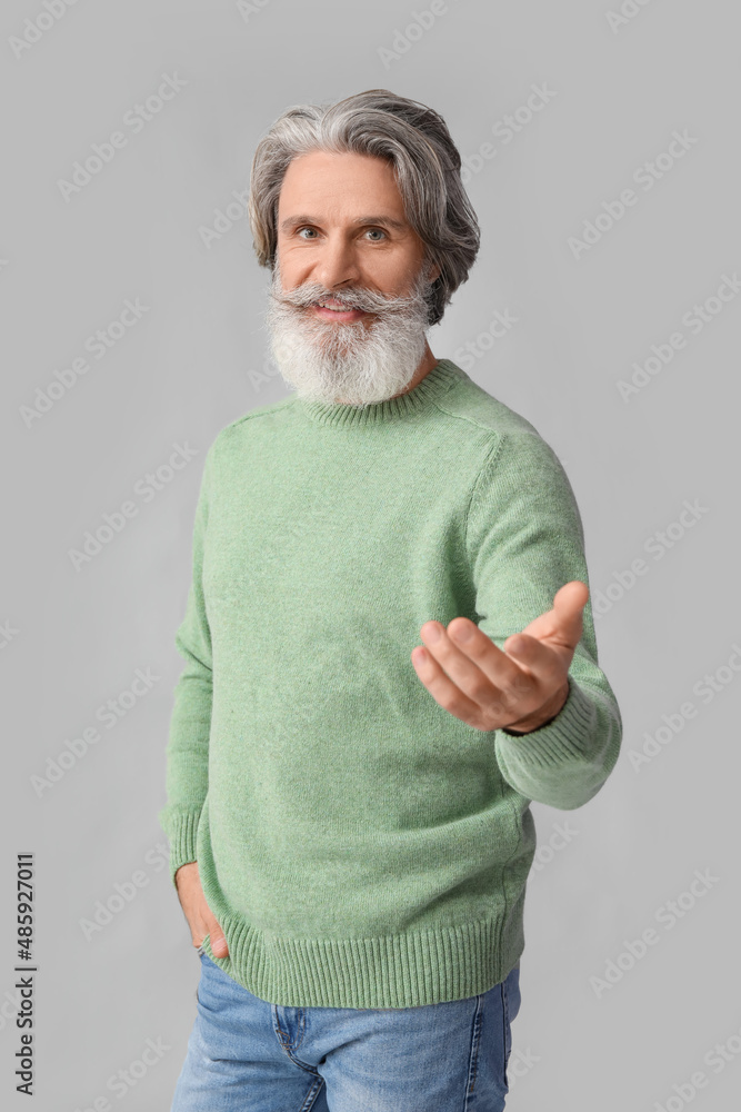 Handsome senior man in knitted sweater on grey background