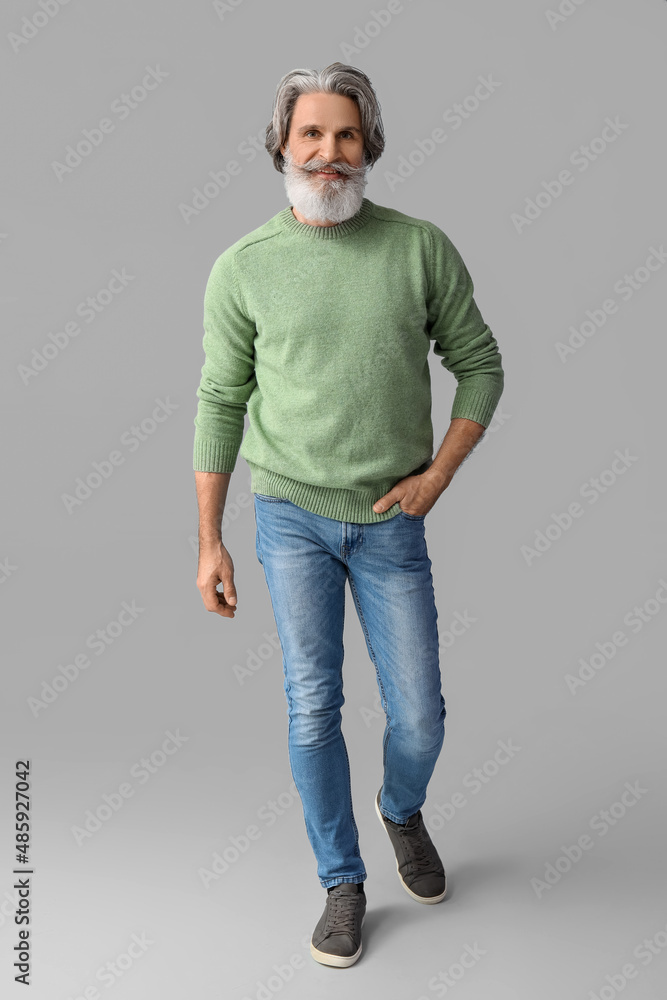 Handsome senior man in knitted sweater on grey background