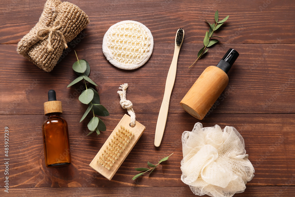 Composition with bath supplies, cosmetics and eucalyptus branches on wooden background