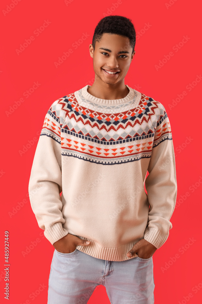 Handsome African-American guy in knitted sweater on red background