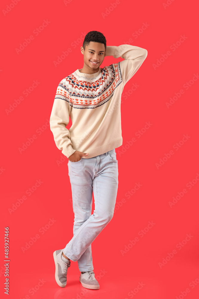 Handsome African-American guy in knitted sweater on red background