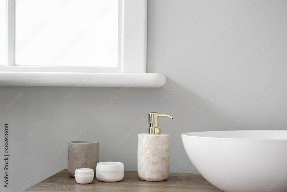 Table with sink and bath accessories near light wall