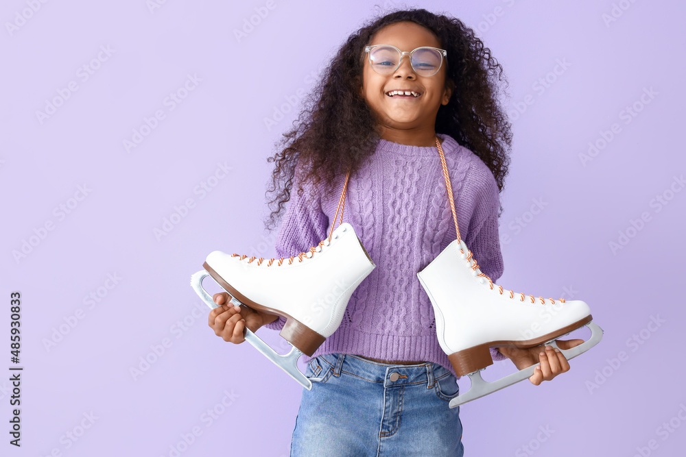 Little African-American girl in eyeglasses with ice skates on lilac background