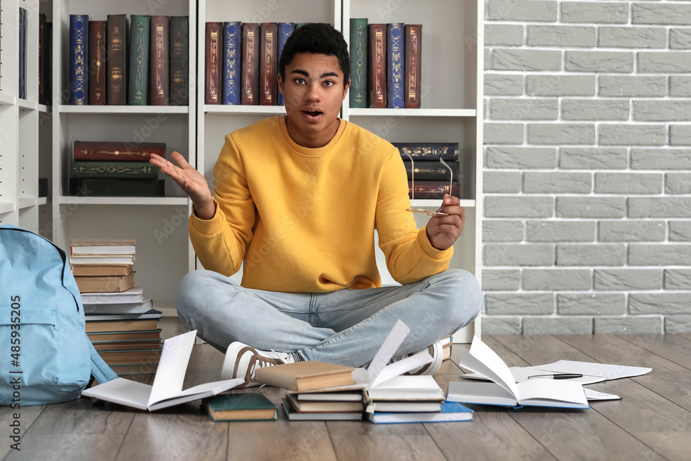 Emotional male African-American student studying in library