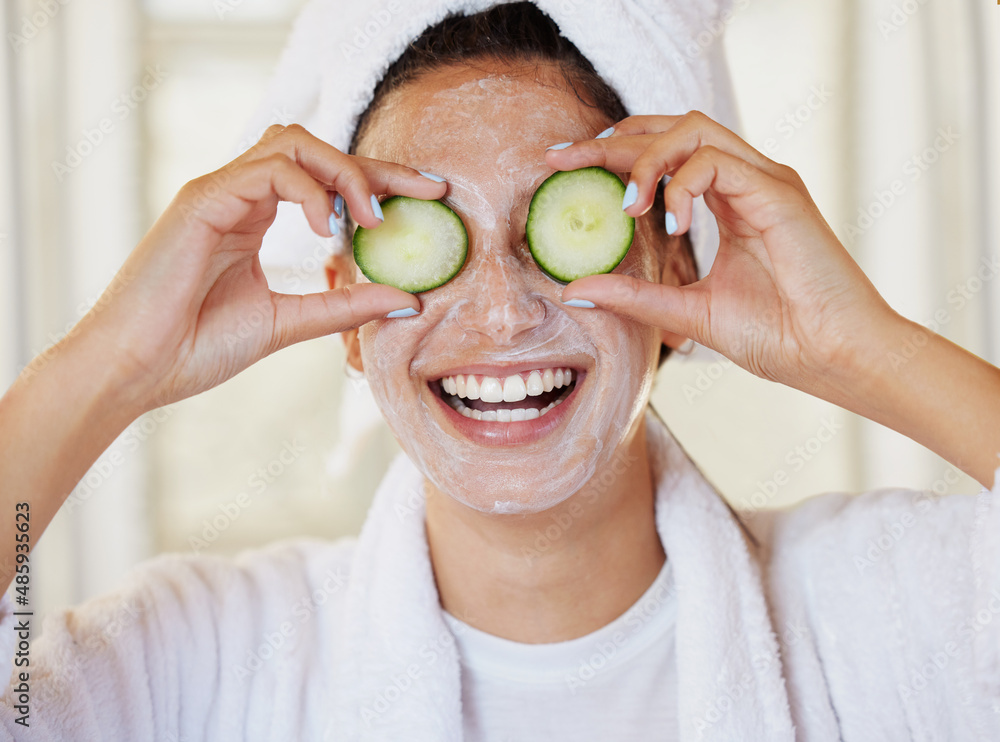 I needed a spa day. Shot of a beautiful young woman holding cucumbers in front of her eye during her