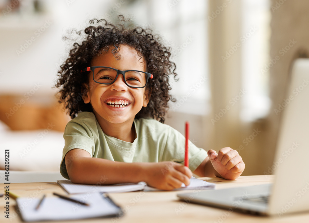 Smiling african american child school boy studying online on laptop at home