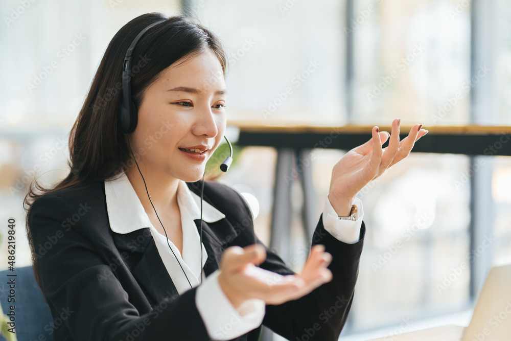 戴着耳机微笑的亚洲女士自由职业者，通过视频与客户交流