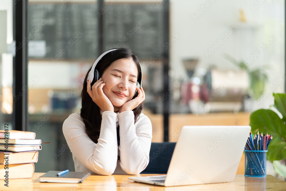 Young Asian female student wearing headphone working and studying from home during the city lockdown