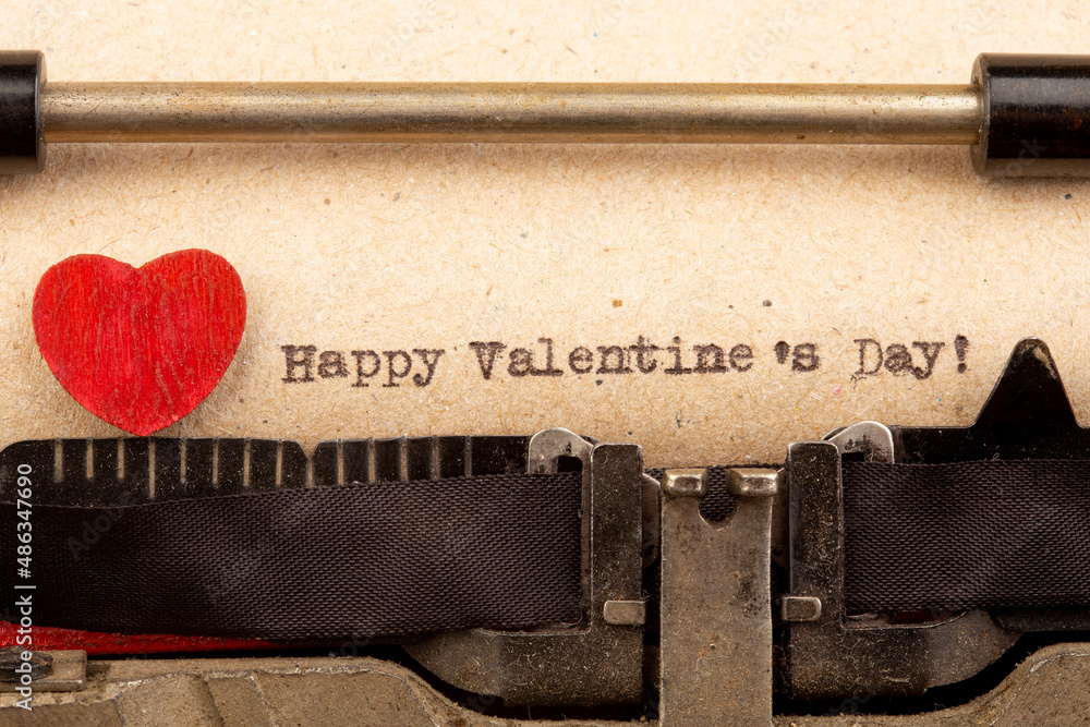 Happy Valentine`s day - phrase on typewriter. Valentines Day greetings concept. Little red wooden he