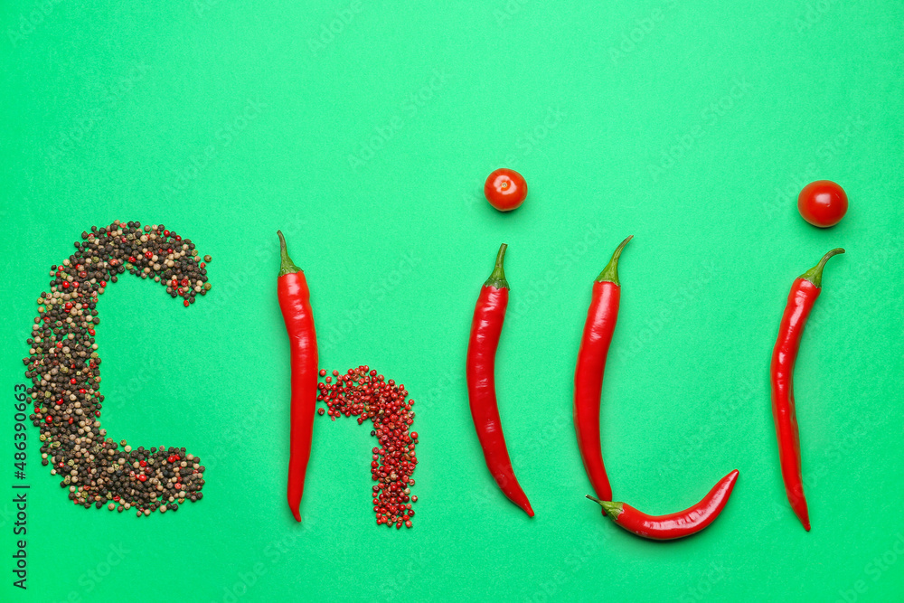 Word CHILI made of peppers, peppercorns and tomatoes on green background